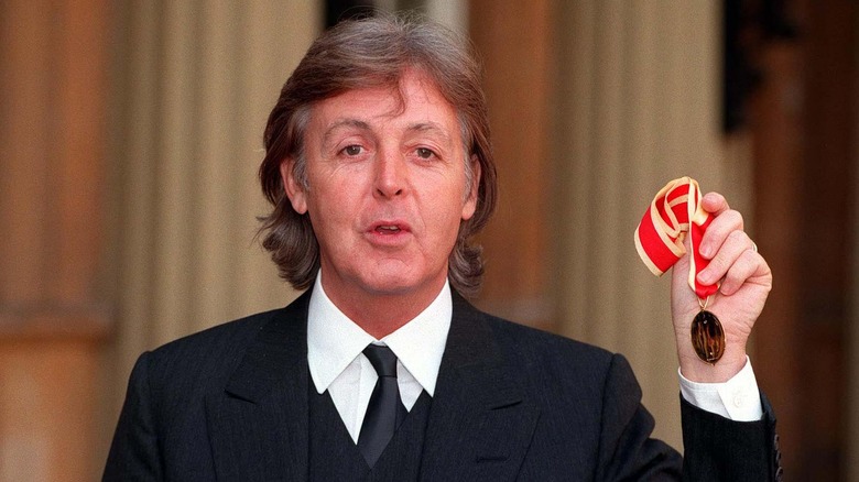 Paul McCartney holds up his medal after receiving knighthood