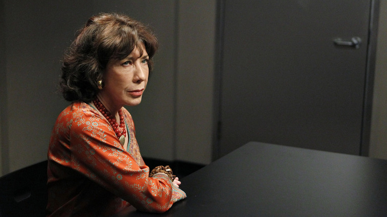 Lily Tomlin seated with arm on table, looking on