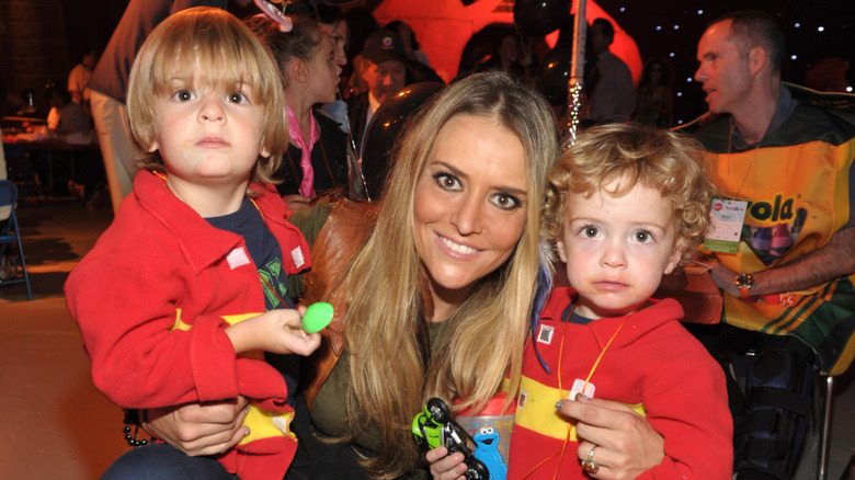 Brooke Mueller smiling and holding young Bob and Max Sheen