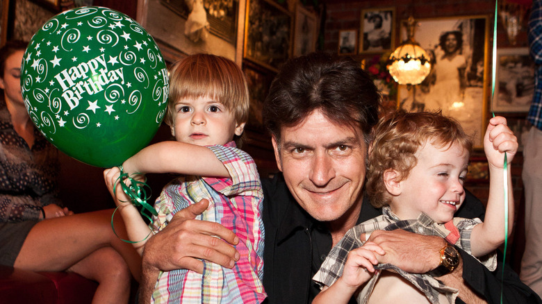 Charlie Sheen smiling and holding Max and Bob Sheen