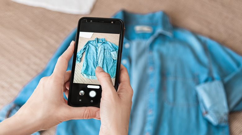 Woman taking photo of denim shirt on smartphone