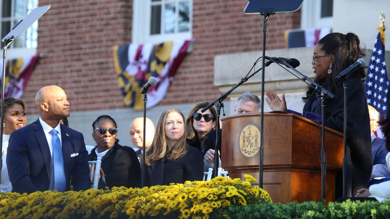 Oprah Winfrey speaking at Governor Wes Moore's inauguration, Chelsea Clinton looking on