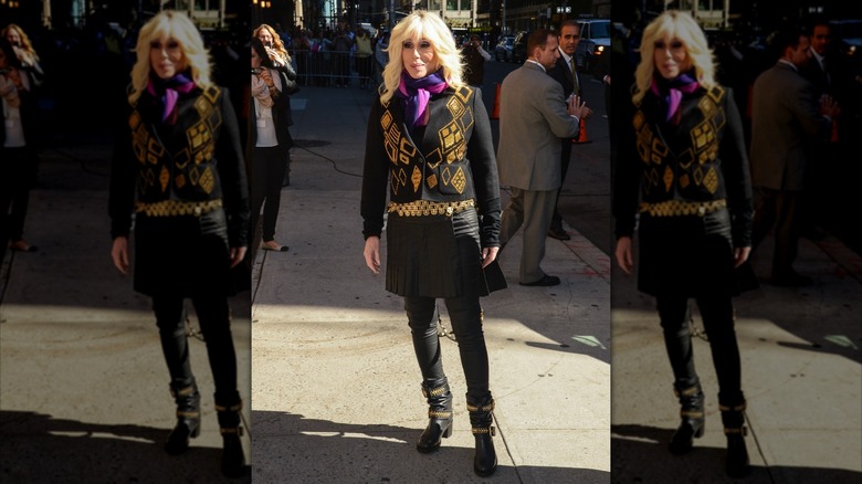 Cher on the sidewalk in black and gold outfit with blond wig