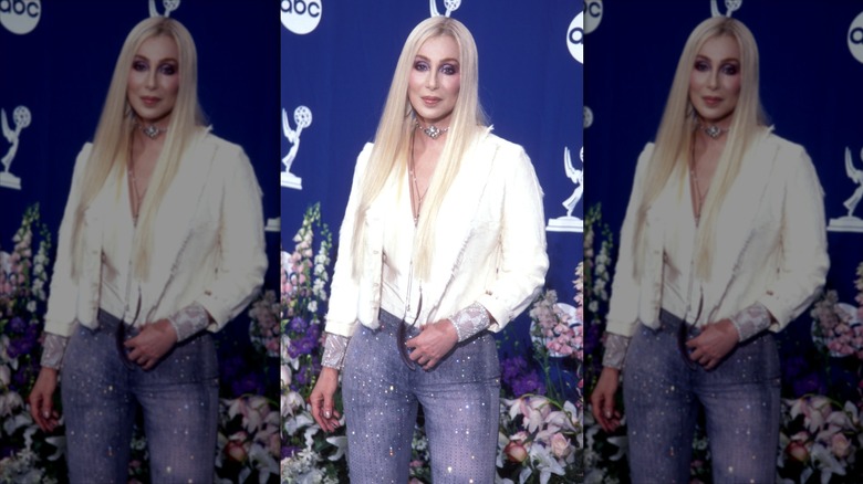 Cher posing for pictures in long, blond wig