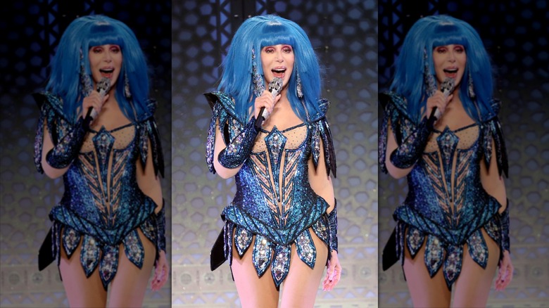 Cher wearing blue wig while singing on tour