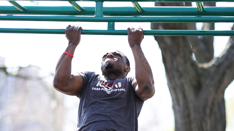 Young man doing chin-ups in the park 