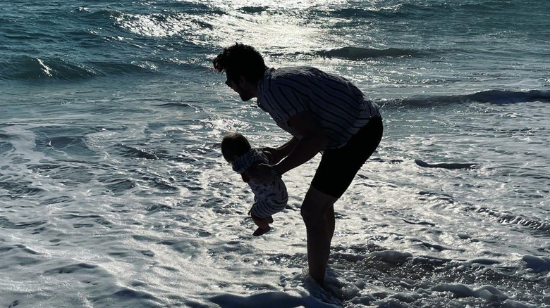 Chris McNally holding his daughter in ocean