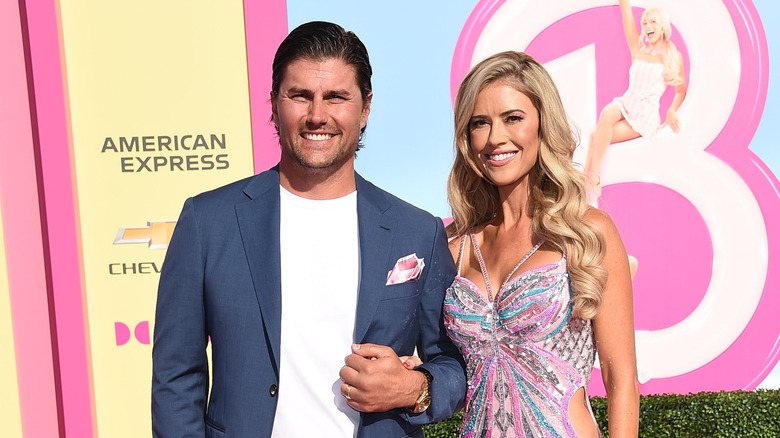 Josh Hall and Christina Haack smiling in front of Barbie poster