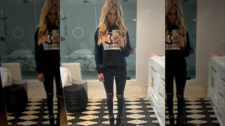 Christina Haack in a black sweater, black pants and taking a selfie