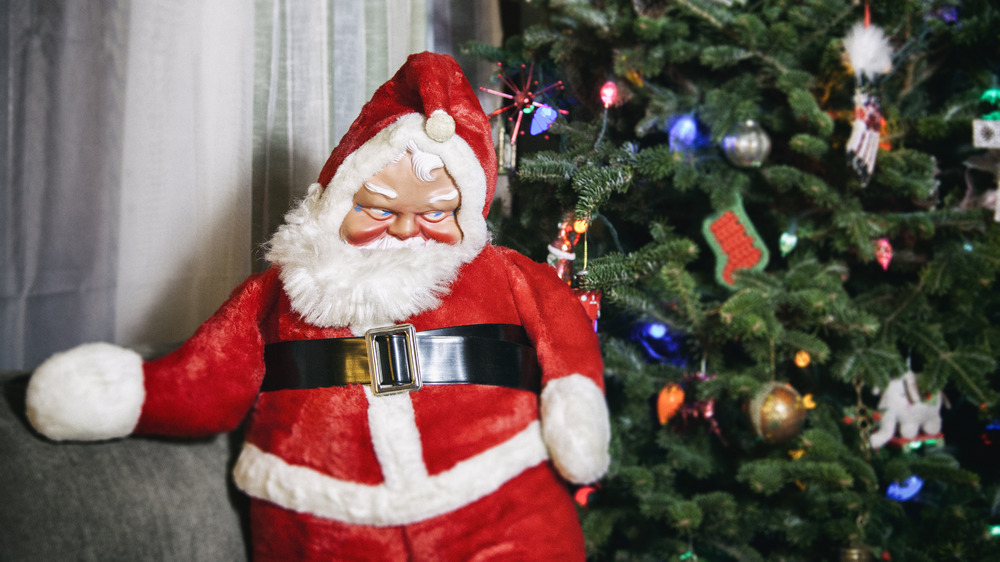 Creepy-looking Santa figurine by tree