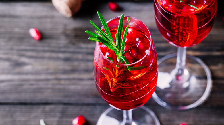 A glass of pomegranate mimosa garnished with herbs