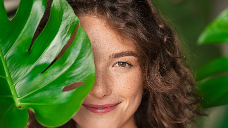 A woman holding a leaf in front of her face