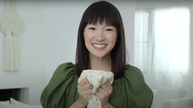 smiling Marie Kondo holds shirt