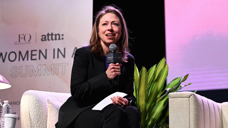 Chelsea Clinton speaking to an audience in a black suit