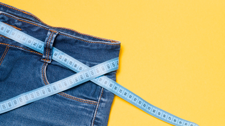 pair of jeans with measuring tape through the belt loops