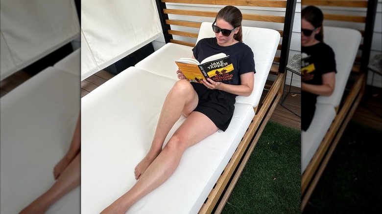 Kasie Hunt lounging on a beach chair with Jake Tapper's book 'All The Demons Are Here'