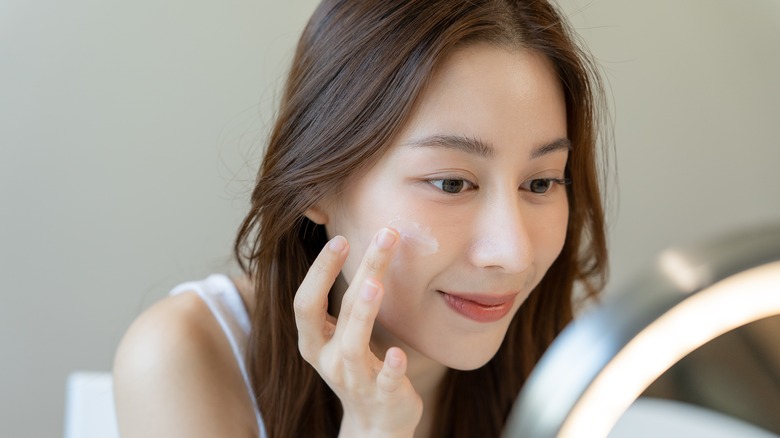 Woman applying skincare product 