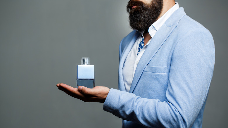 man holding fragrance bottle 