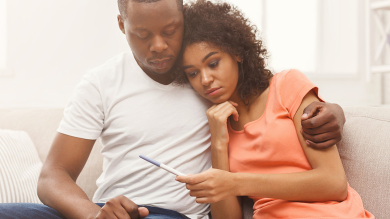 Man and woman look sadly at pregnancy test 