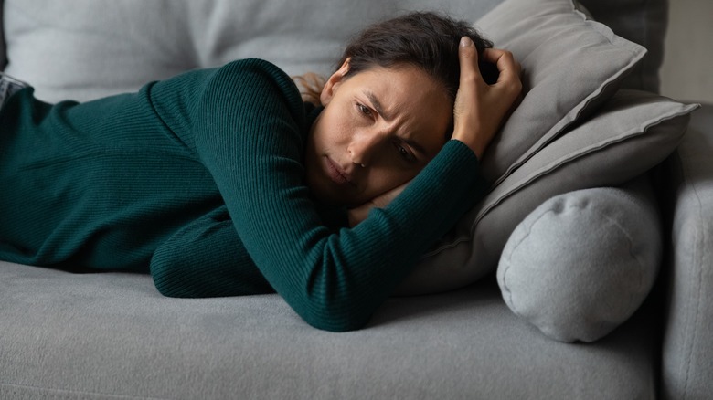 Woman lying on couch frowning