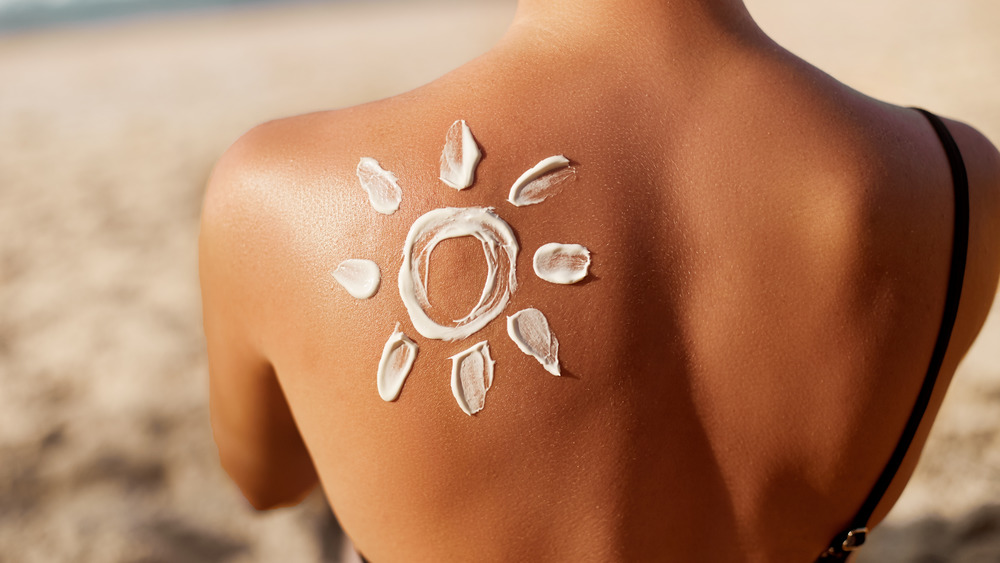 A woman with a sunscreen sun on her tan back 