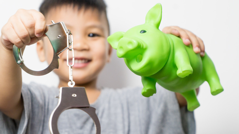 child holding handcuffs and a green pig