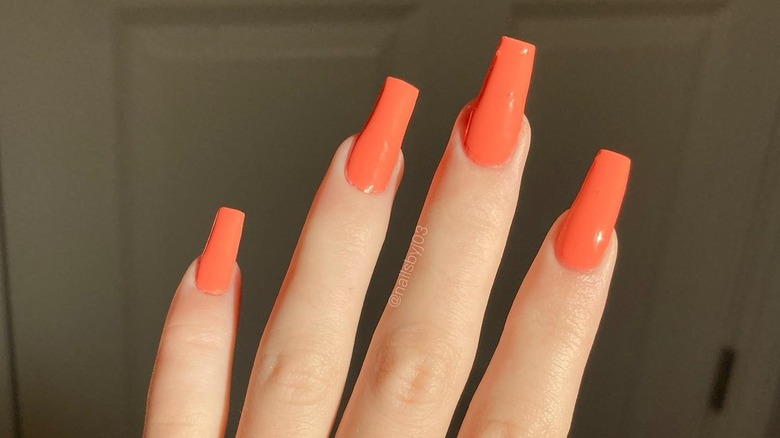 Woman with bright coral nails