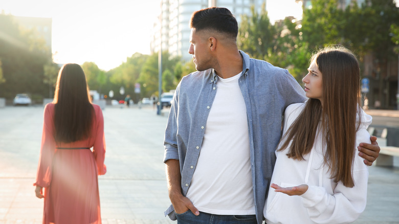 Man looks at another woman while with his girlfriend