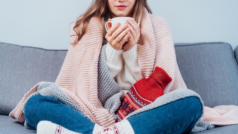 woman on couch with heating pad