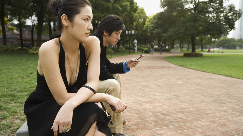 couple sitting apart on bench