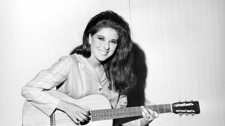 Bobbie Gentry smiles while strumming a guitar