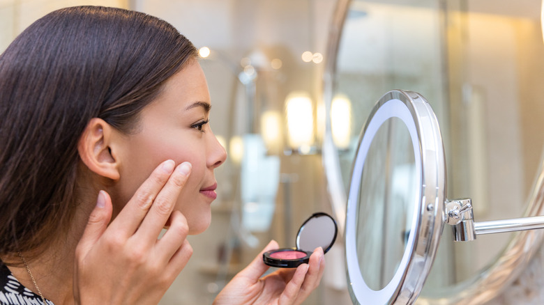 woman applying cream blush