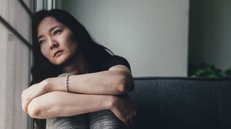 Asian woman looking into the distance with her head against a wall