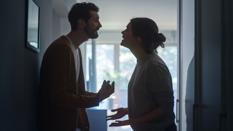 Couple arguing in a dark hallway 