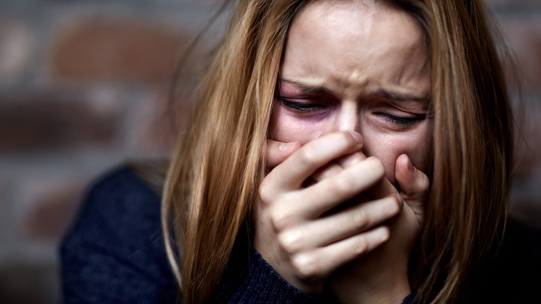 woman crying hard and covering her mouth