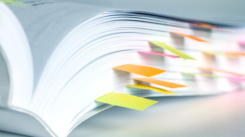 closeup of white pages marked with different colored sticky notes