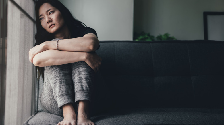 young woman looking upset, hugging her legs