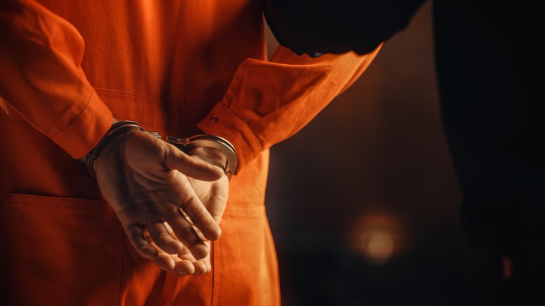 handcuffed convict in an orange jumpsuit