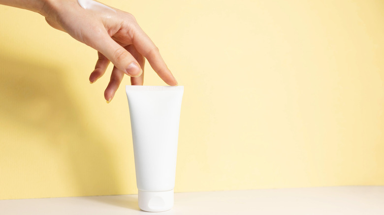 A woman touching a tube of hand cream 