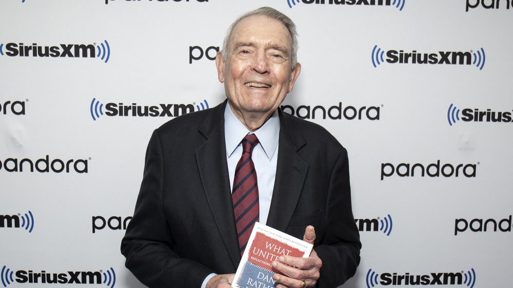 Dan Rather holding his book