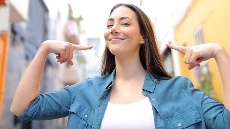 Smiling woman pointing at herself