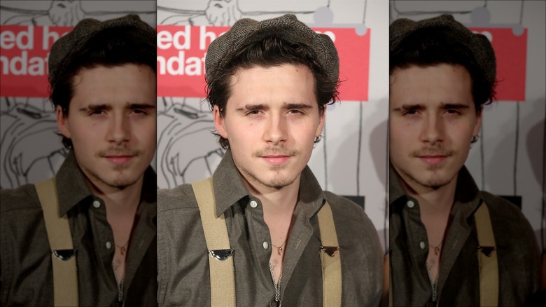 Brooklyn Beckham posing in suspenders and an old-timey cap