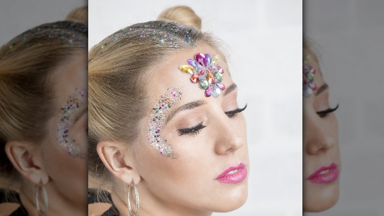 A woman with glitter makeup and glitter hair part