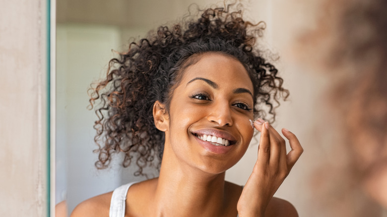 A woman moisturizes her skin.