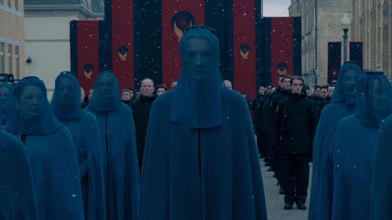 Leah (Angela Vint) and Grace (Paula Boudreau), shown walking in procession in Gilead for Fred's funeral