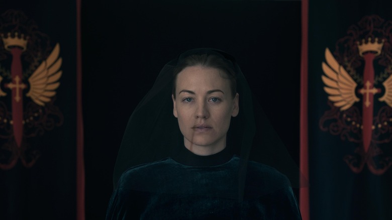 Serena (Yvonne Strahovski) stands in front of Gilead Commander mourning flags