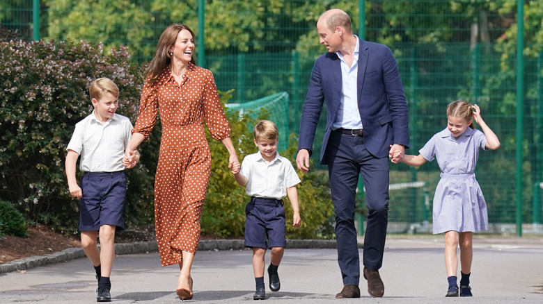 Kate MIddleton and Prince William smiling and walking with Prince George, Princess Charlotte, and Prince Louis 