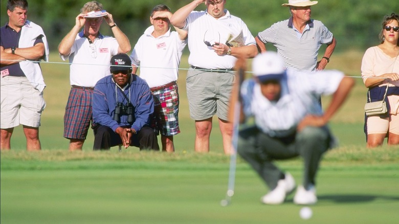 Earl Woods watches Tiger Woods play