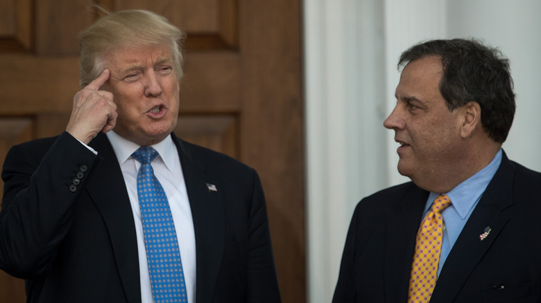 Donald Trump points at his head while Chris Christie looks confused