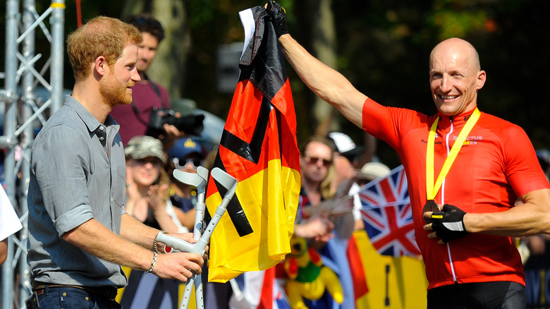 Prince Harry holding crutches for Invictus Games medal winner